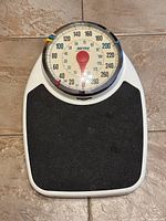 Front view of the Metro mechanical weight scale showing the round dial with markings up to 280 pounds and a black textured platform.
