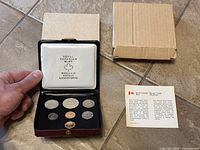 Seven 1977 Canadian coins displayed in opened Royal Canadian Mint case along with original cardboard box and information card.
