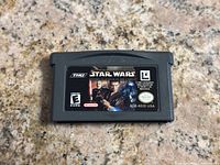 Front view of gray Nintendo Gameboy Advance cartridge showing label for Star Wars II: Attack of the Clones game with ESRB rating and logos.