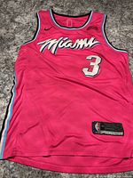 Front side of pink Miami Heat Dwyane Wade basketball jersey with team name, number 3, Nike logo, and size tag 48.