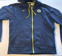 Front view of the black Nike hoodie with Fenerbahce Sports Club patch, yellow zipper, and drawstrings laid flat.