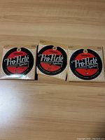 Three sealed packs of D'Addario Pro-Arte EJ45 classical guitar nylon strings placed side by side on wooden surface.