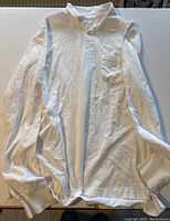 Full front view of white long sleeve polo shirt showing collar, buttons, pocket and fabric texture.