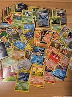 Overall spread of many Pokémon cards laid out on a wood surface, showing various characters and card types including holo and EX cards.