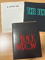 Three press kit covers/booklets shown: 'A Little Sex', 'The Fly', and 'Black Widow'.