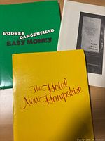 Press kits or folders for three films: 'The Hotel New Hampshire' in yellow cover, 'Easy Money' with Rodney Dangerfield in green cover, and a black and white page titled 'Broadway' listing actors.