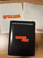 Three press kit folders for films Up the Creek, Endangered Species, and Under Fire on a wooden surface.