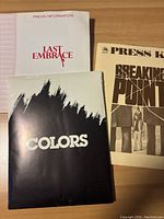 Three vintage press kits for Last Embrace, Breaking Point, and Colors on a wooden surface.
