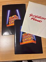 Two laminated folders, one with 20th Century Fox 20th anniversary logo and one with 'Just Between Friends' title embroidered in red on white fabric.