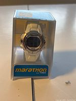 Front view of new Timex Marathon digital watch in original clear display packaging showing dial and branding.