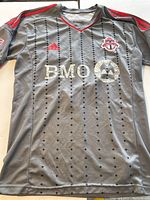 Front view of Toronto FC gray jersey with red trim, BMO logo, and team crest.