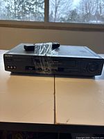 Front view of Sony VHS player with cassette slot, control buttons, and taped handle.