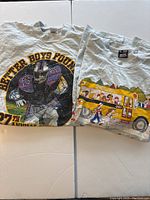 Two vintage XL T-shirts displayed flat showing front graphics: one 'Better Boys Football' with a football player, the other a school bus with kids illustration.
