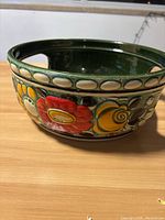 Side view of vintage West German ceramic fruit bowl showing colorful floral designs and handle cutouts.
