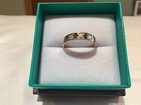 Top view of ring in green jewelry box showing alternating diamonds and sapphires