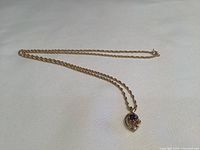 Full length twisted rope chain laid flat with swirl pendant at center