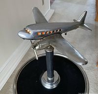 Close-up of silver-toned airplane model showing amber-lit windows and propeller