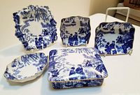 Front view of all five Royal Crown Derby Mikado blue and white porcelain pieces arranged on white surface