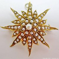 Front view of starburst brooch showing central prong-set pearl and radiating rays