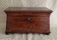 Front view of closed mahogany tea caddy showing bun feet and key escutcheon