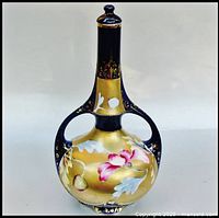 Front view of cobalt blue and gold hand painted floral bottle with lid and dual handles.
