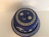 Top view of cheese dome lid showing handle and decorative oak leaves and flower motifs.