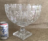 Full view of the large cut crystal pedestal bowl with soda can for scale showing the intricate geometric cut patterns and scalloped rim.