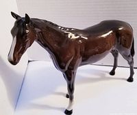Full side view of large brown horse figurine with white accents on nose and feet, showing overall condition and size