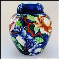 Front view of cobalt blue ginger jar with hand-painted raised floral design in multiple colors.