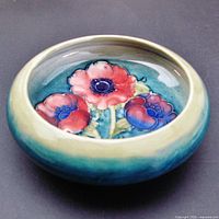 Front view of the bowl showing the three tube-lined anemone flowers in pink, blue and purple against a teal and green background.