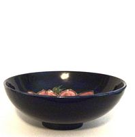 Side view of the Moorcroft bowl showing deep cobalt blue exterior and footed base.