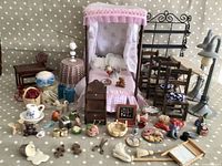 Wide shot showing all vintage wooden dollhouse furniture including canopy bed, table, chairs, and small accessories spread out on a polka dot surface.