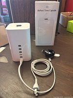 Front view of AirPort Time Capsule tower with original box and cables on table
