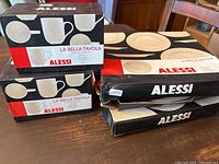 Original boxes for Alessi La Bella Tavola cups and plates, labeled with brand and series name.