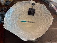 Front view of the large silver decorative bowl with a Sharpie marker for scale on wooden surface