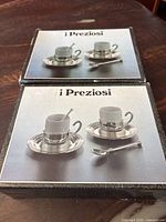 Two boxed i Preziosi espresso sets each showing a cup, saucer, and spoon on the box top.