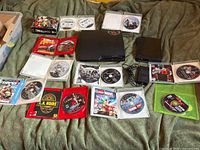 Full lot view showing PS3 console, Wii console, multiple game discs and cases, power cord, all items laid out on blanket.