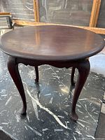Full view of round mahogany table showing Queen Anne cabriole legs and scalloped apron.