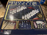 Box showing the 'Glass & Wood 7 Game Set' branding with images of chess, backgammon, checkers, and other games included