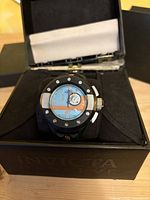 Photo of Invicta Reserve Men's Rally S1 watch inside its open black box, showing the dial and bezel details clearly.