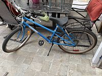 Full side view of the blue ladies bike showing frame, tires, saddle, and handlebars.
