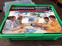 Closed green plastic storage box with Lego Mindstorms label on top showing children interacting with the kit and computer software.
