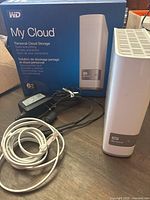 WD My Cloud 6TB personal cloud storage device with original box, power adapter and Ethernet cable on wooden surface.