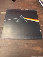 Front cover of Pink Floyd Dark Side Of The Moon vinyl record showing the iconic prism with rainbow light beam design. Cover has visible edge wear and scuff marks.