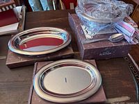 Two oval serving platters with mirror finish on top of boxes with 'Rotonda' label.