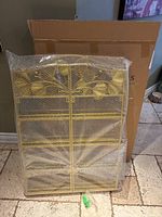 Photo of gold metal storage shelves wrapped in bubble wrap leaning against a brown cardboard box.