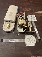 Weiser electronic lock components including lock mechanism, keypad button pads, keypad circuit strips, latch bolt and screws arranged on wooden surface.