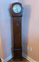 Full frontal view of tall wooden grandmother clock with Art Deco style details, showing overall condition and design.