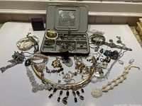 Wide view of the entire collection of costume jewelry laid out on a flat surface showing multiple necklaces, earrings, bracelets, rings and brooches.