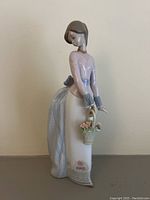 Front view of the Lladro porcelain figurine showing the figure's face, basket with flowers, and detailed gown.